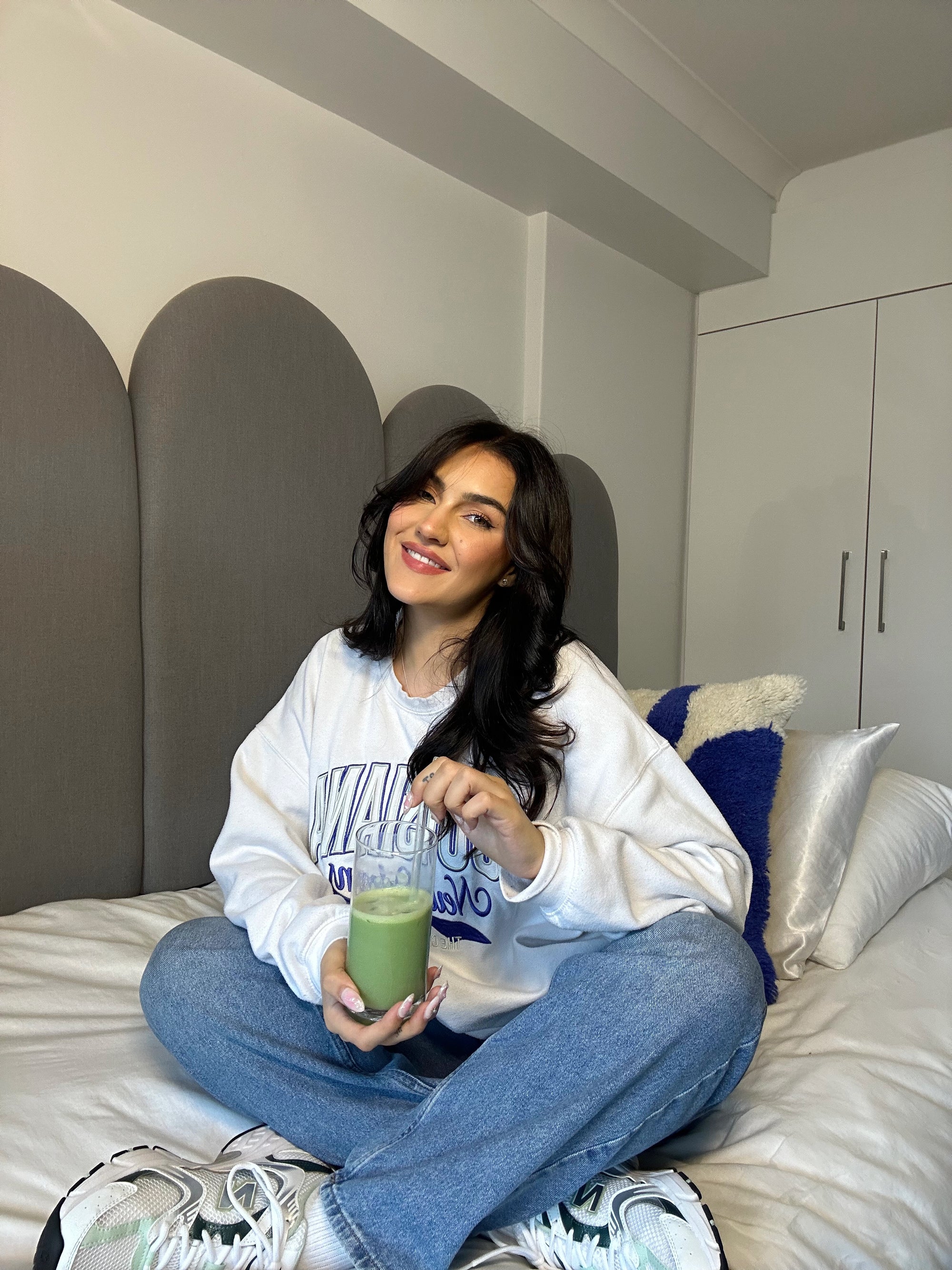 girl sitting on a bed holding matcha