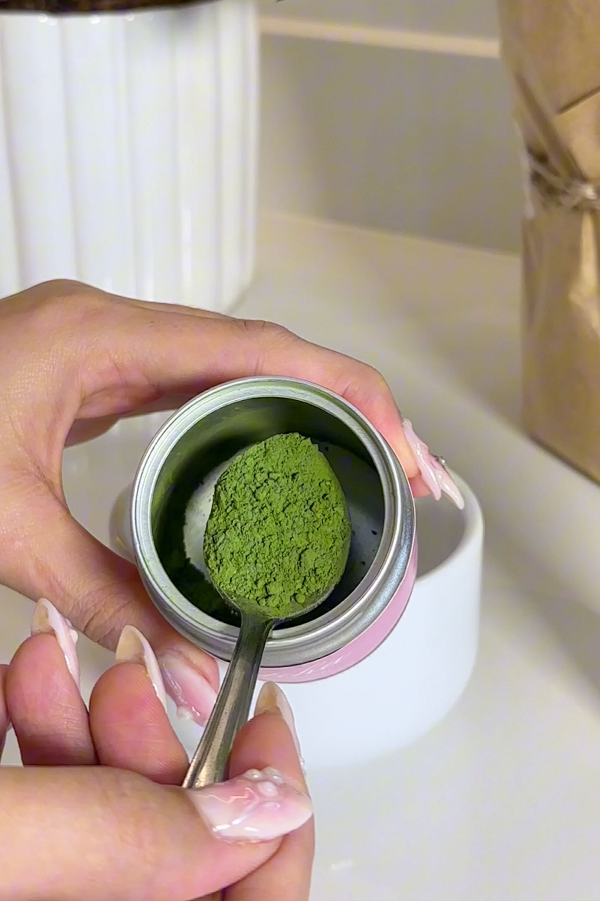 spoon of matcha green tea powder taken from matcha tin