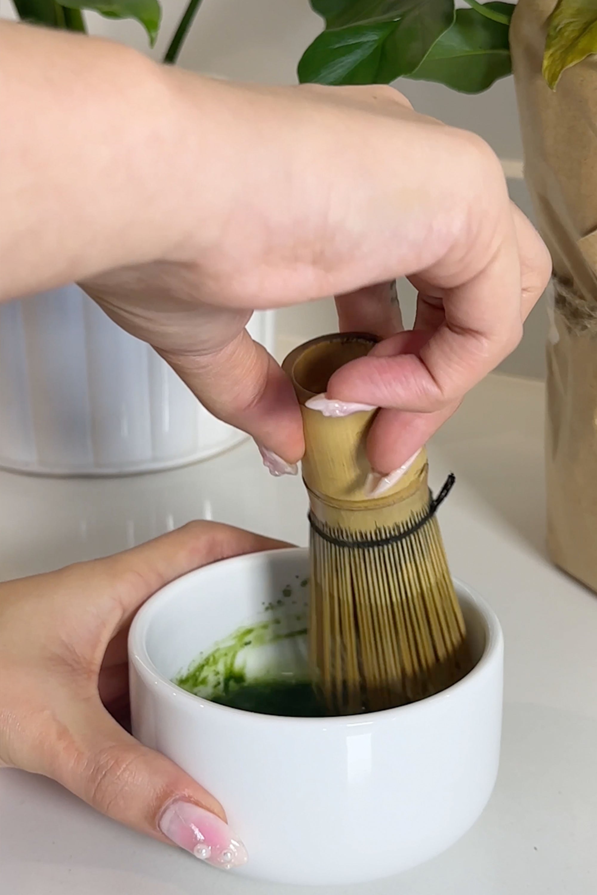 whisking matcha green team in a bowl with a bamboo whisk chasen