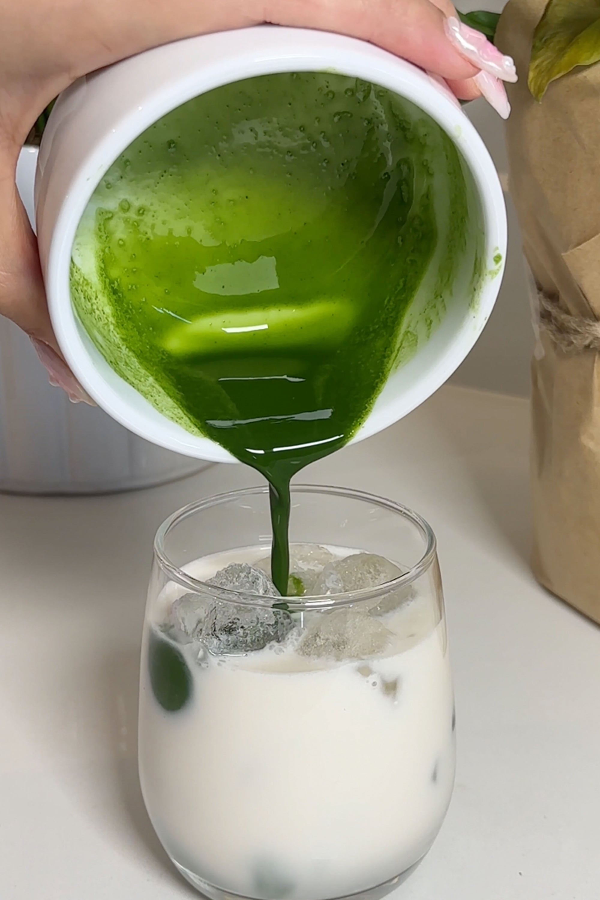 matcha green tea mixture poured in to glass with milk and ice